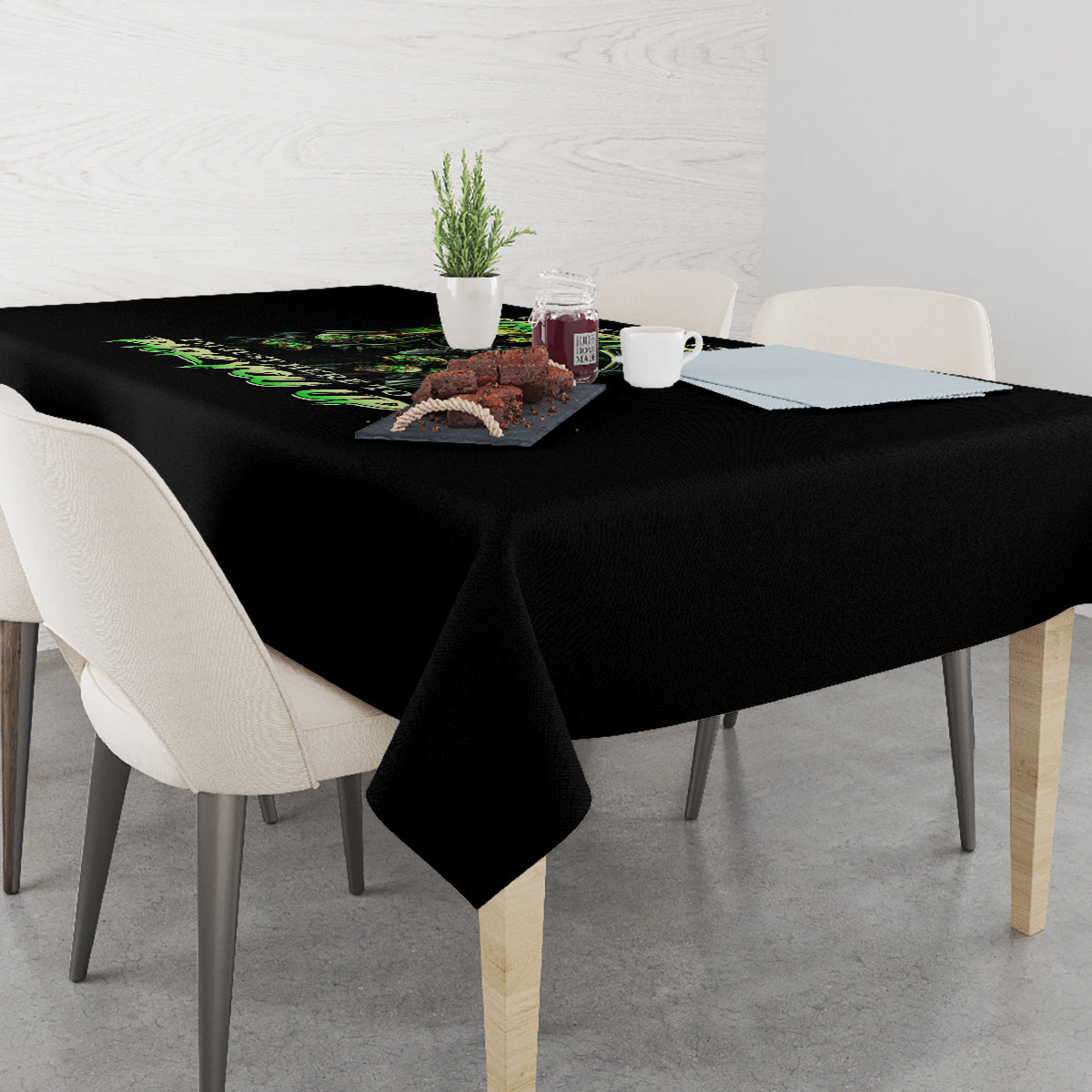 Black rectangular tablecloth with green skull graphic on a dining table surface