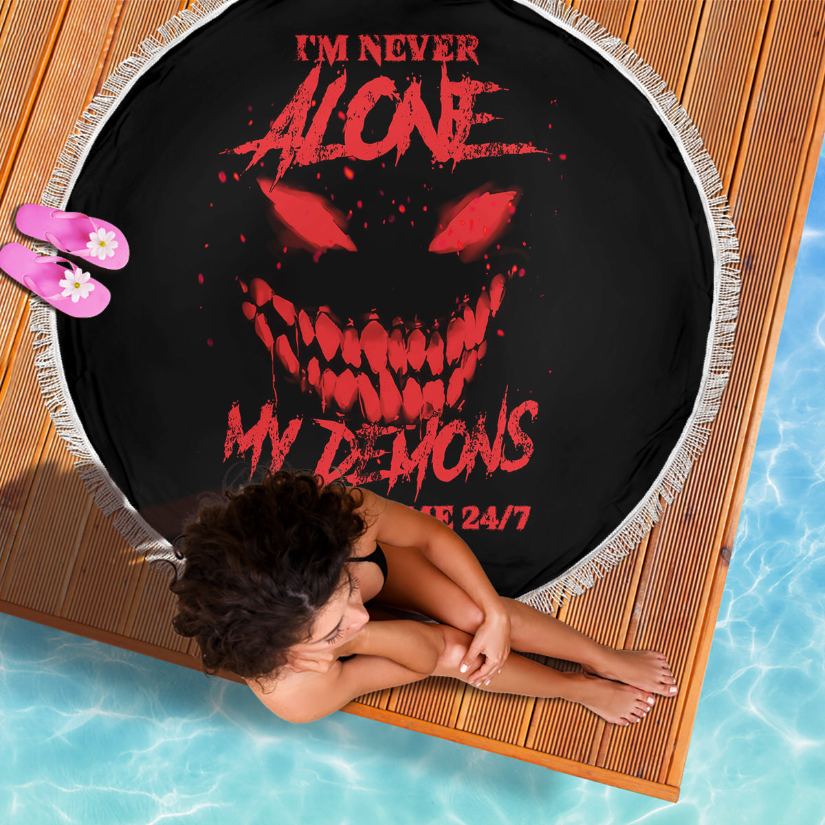 Black round beach blanket with red skull graphic and white fringe edge, 24/7 text