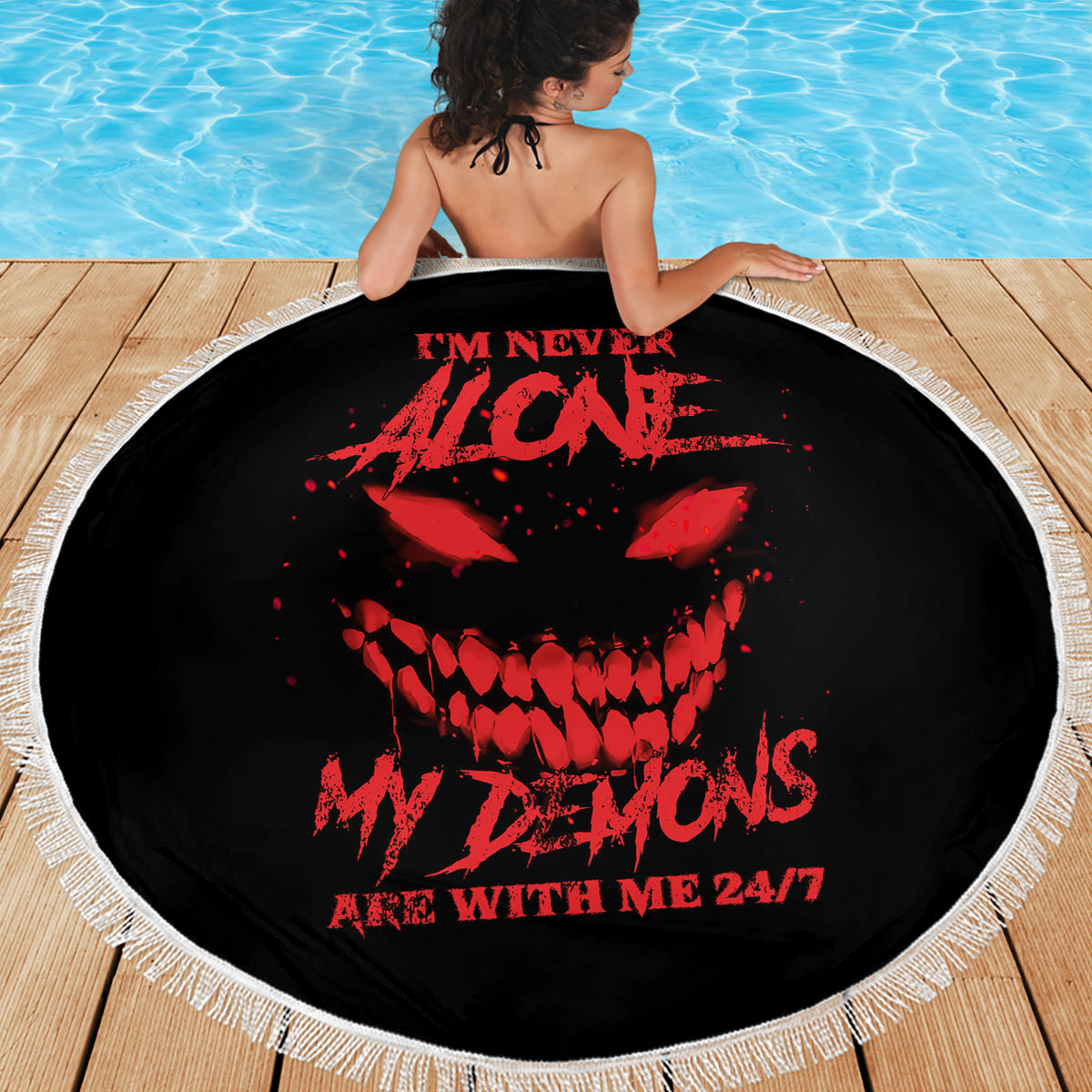Black round beach blanket with red skull graphic, white fringe edge, 24/7 text