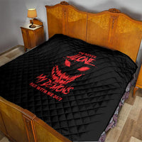 Black quilt blanket with red demon graphic on bed, diamond quilted surface