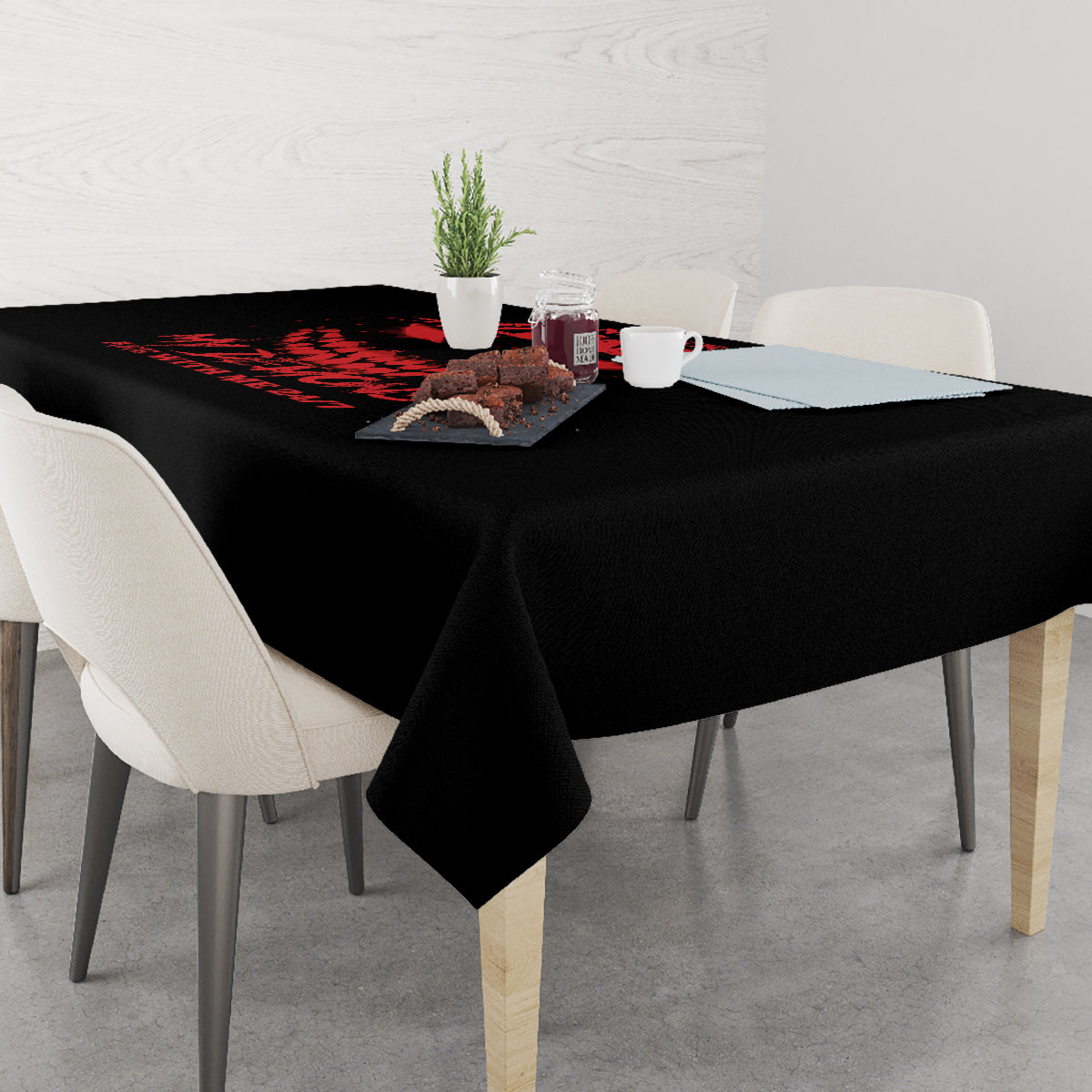 Black tablecloth with red demon graphic, set on dining table with cups and chairs