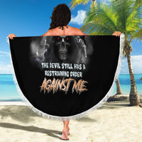 Round black beach blanket with white fringe and skull reaper graphic, held out
