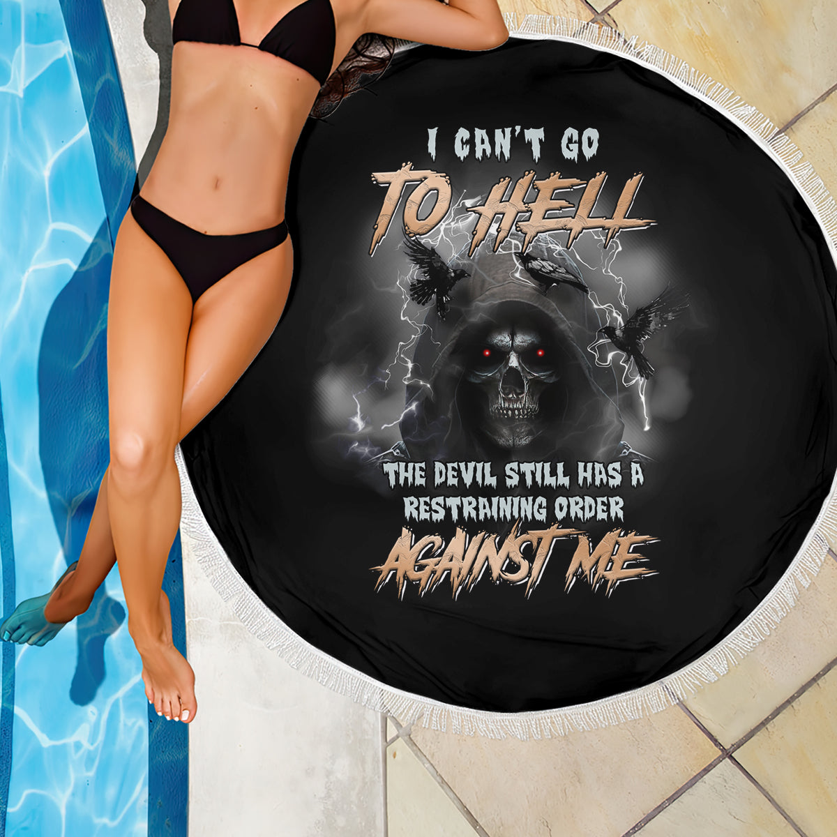 Round black beach blanket with white fringe and skull reaper graphic, close view