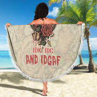 Round beach blanket held flat; skull-and-rose design with red text, white fringe border