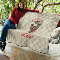 Cream quilt draped on sofa with skull graphic and red lettering, diamond stitched