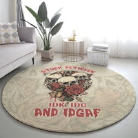 Round area rug with skull-and-rose center print and red slogan on beige-gray