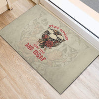Gray rubber doormat with skull and rose graphic and red slogan text