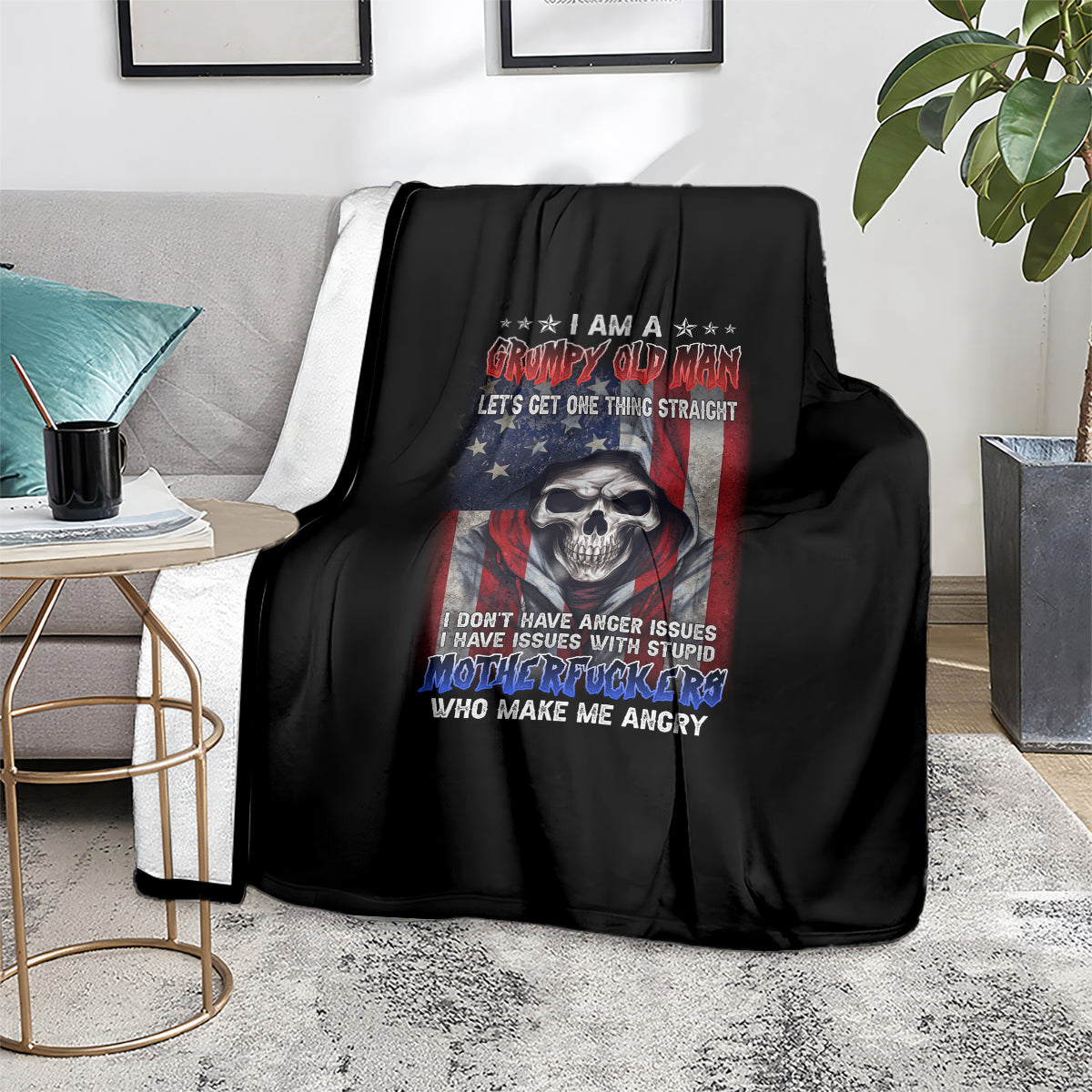 Black graphic throw blanket with skull and patriotic slogan, displayed on a sofa
