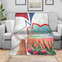 Multicolor Dutch windmill and tulip throw blanket draped over gray sofa
