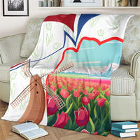 Multicolor Dutch windmill and tulip blanket on cream sofa with open book nearby