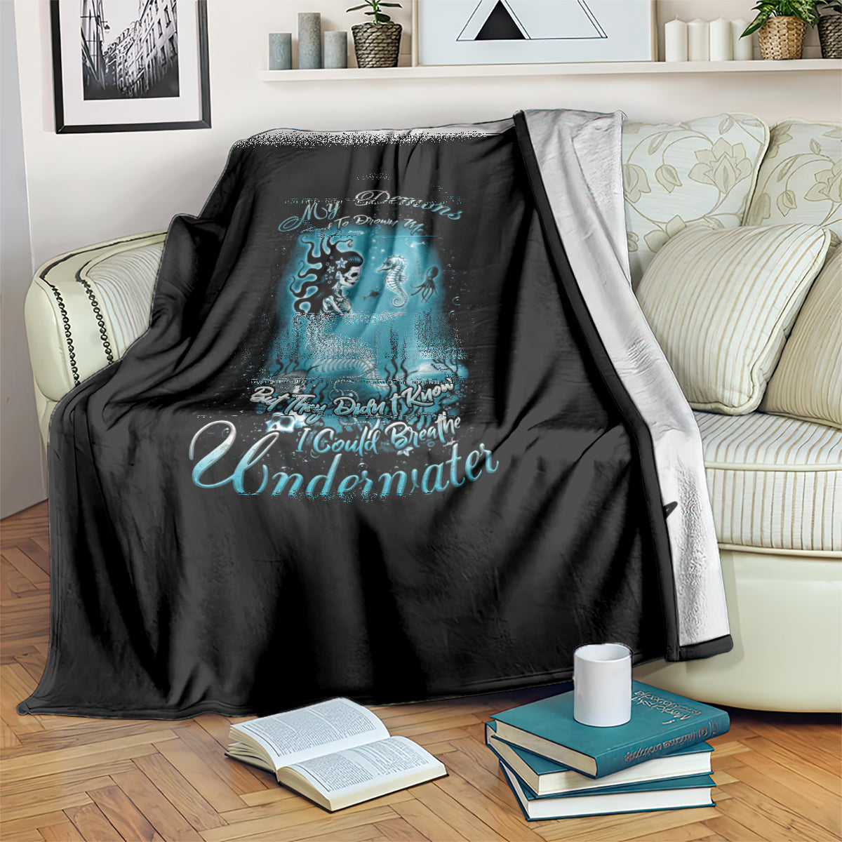 Black mermaid graphic blanket draped over couch, teal undersea figure artwork