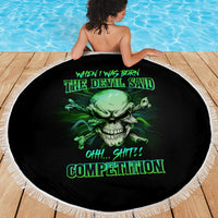 Round black beach blanket with green skull graphic and white fringe border, shown draped