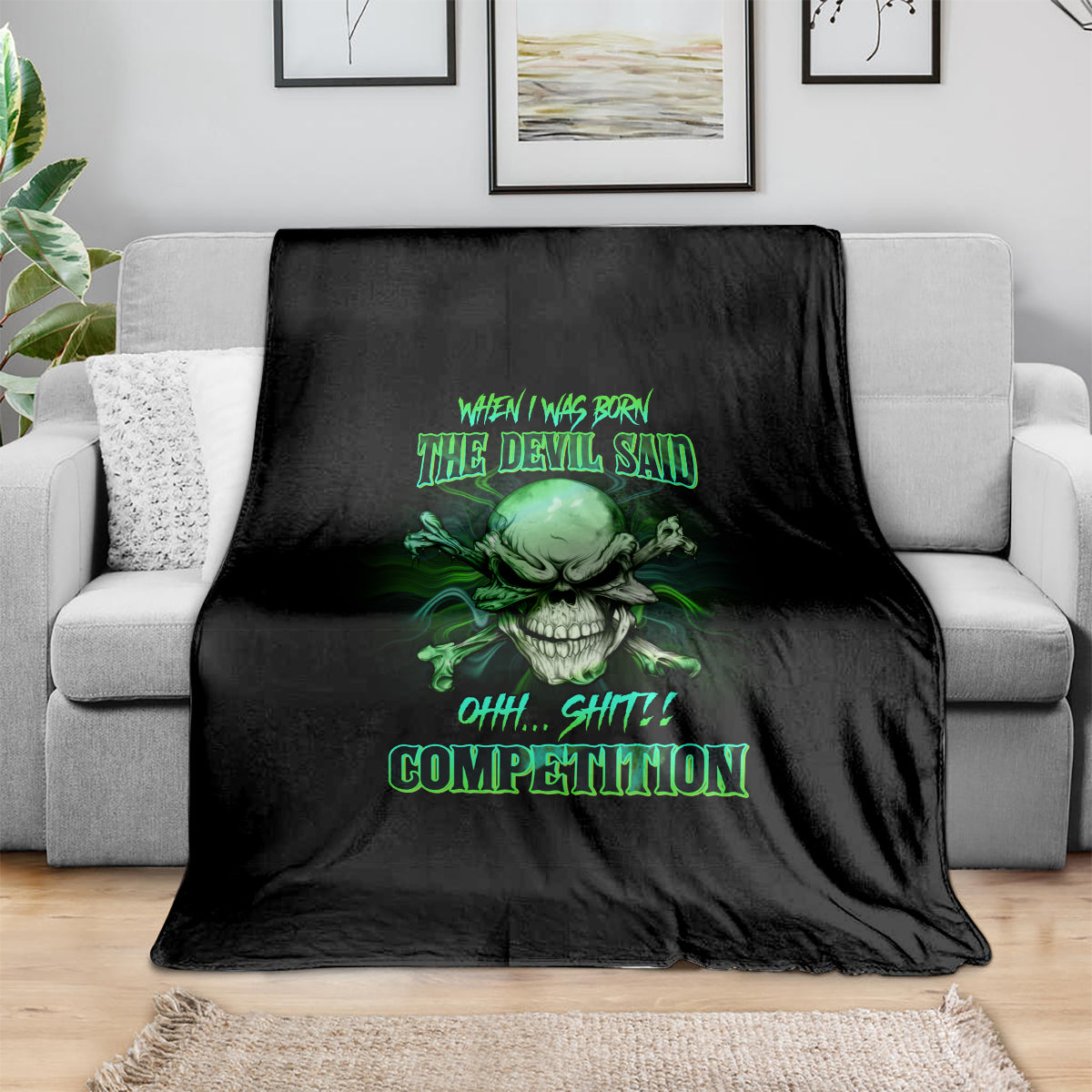 Black skull graphic throw blanket with neon-green text design, folded on a couch