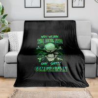 Black skull graphic throw blanket with neon-green text design, folded on a couch