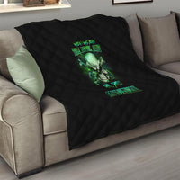 Black quilt blanket on gray sofa with green skull artwork and neon text, quilted.