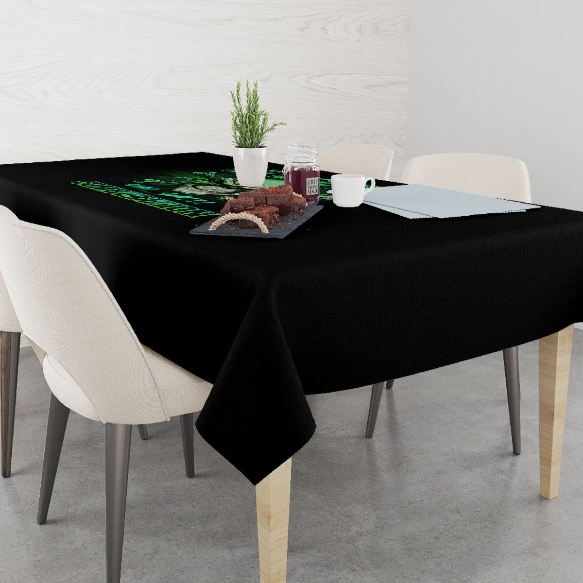 Black printed tablecloth on dining table with green skull graphic at center.