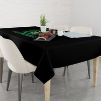 Black printed tablecloth on dining table with green skull graphic at center.