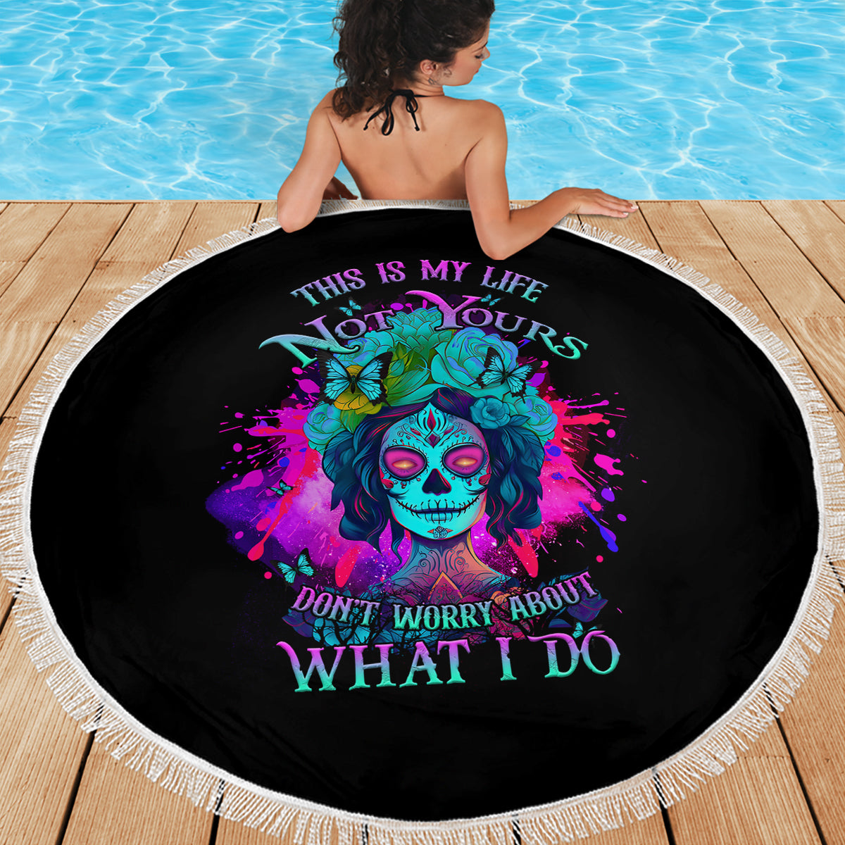Round black beach blanket with colorful skull and flowers design, white fringe trim