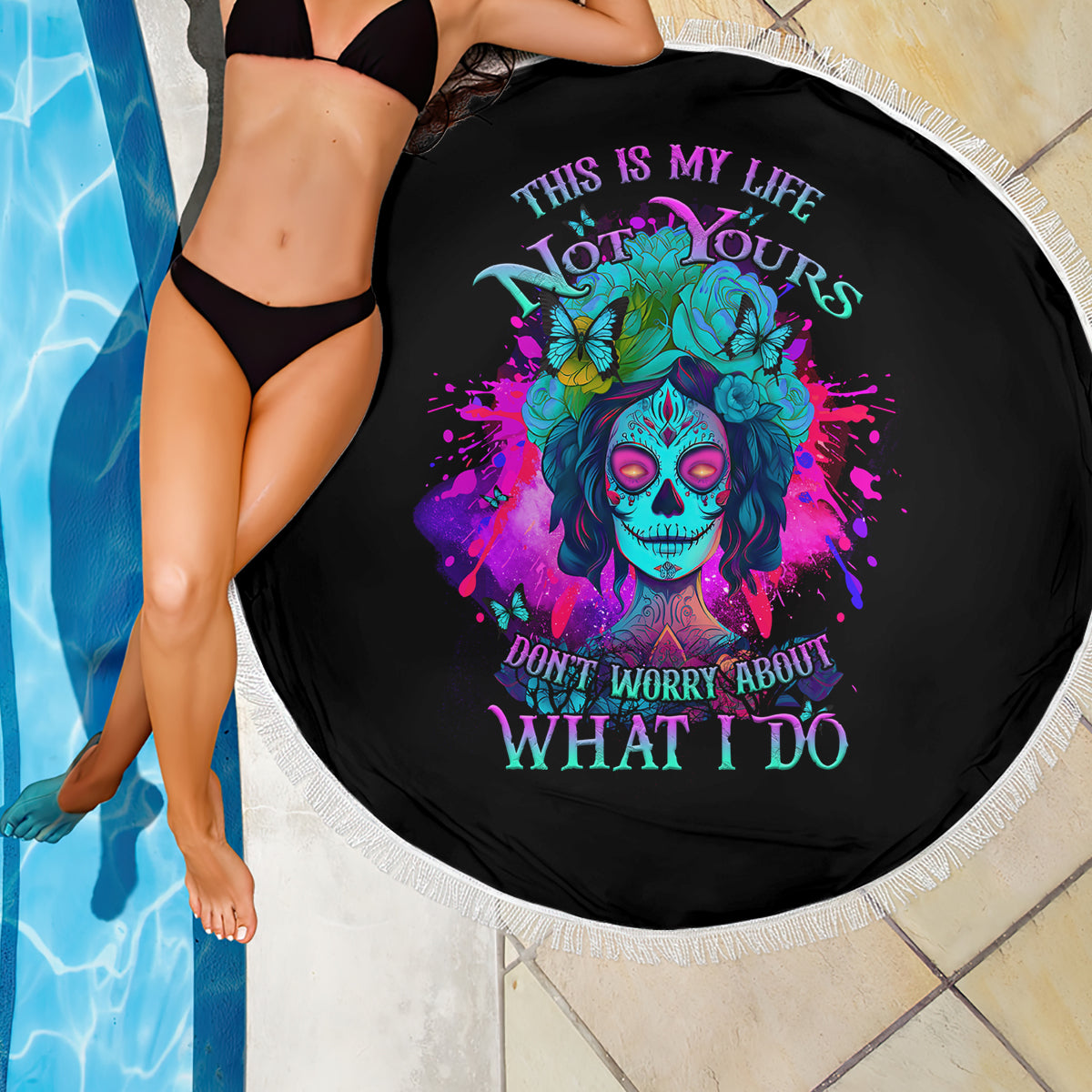Round black beach blanket with colorful skull floral artwork and white fringe edge