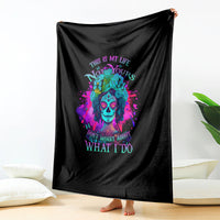Black throw blanket with colorful skull artwork and motivational text, hanging vertically.