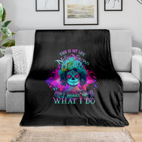 Black fleece blanket with colorful sugar skull graphic and quote text, laid on a sofa.