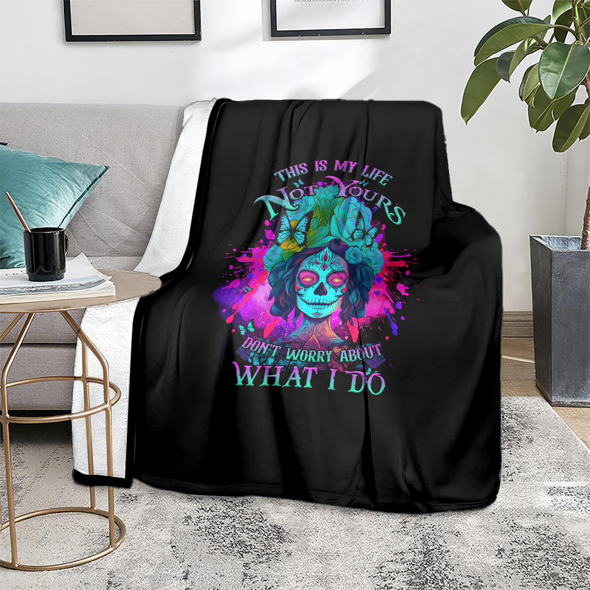 Black throw blanket with colorful skull design and motivational quote text on display.