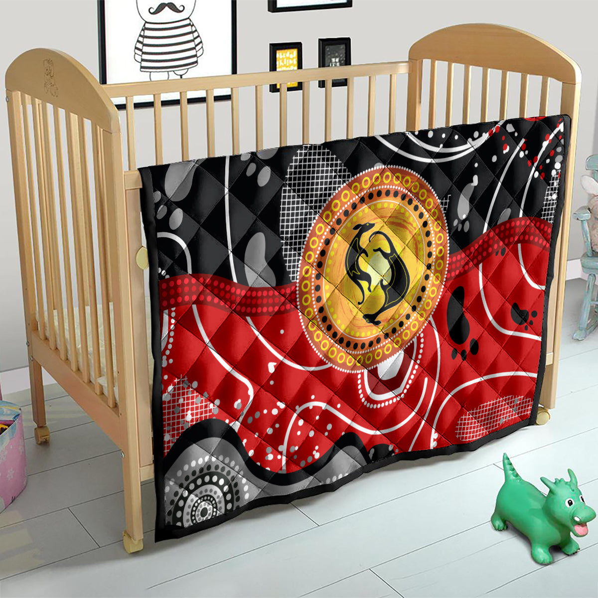 Multicolor quilt over a baby bed with black and red abstract dots and a golden kangaroo circle