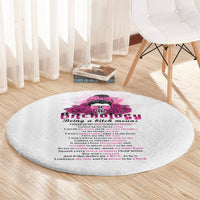 Round gray shag-style rug with pink skull rose graphic and text