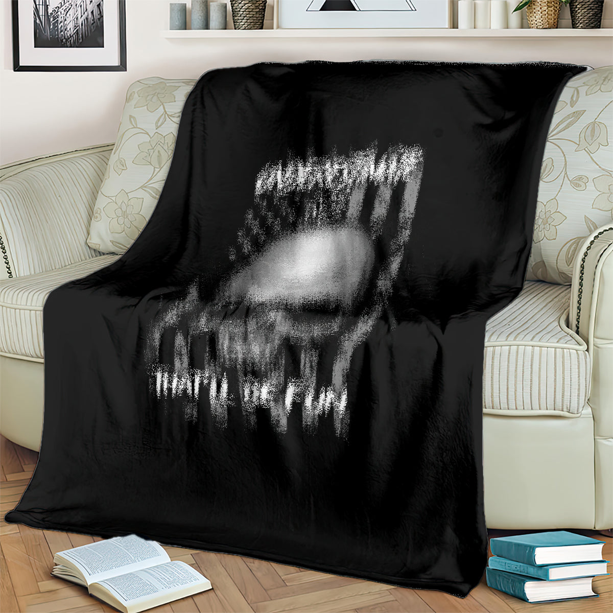 Black throw blanket close-up with faded skull graphic and 'UNDERSTIMATE ME' text