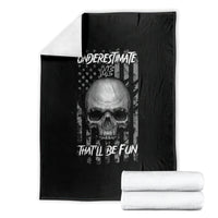Black blanket with centered skull graphic, folded, with stacked white towels