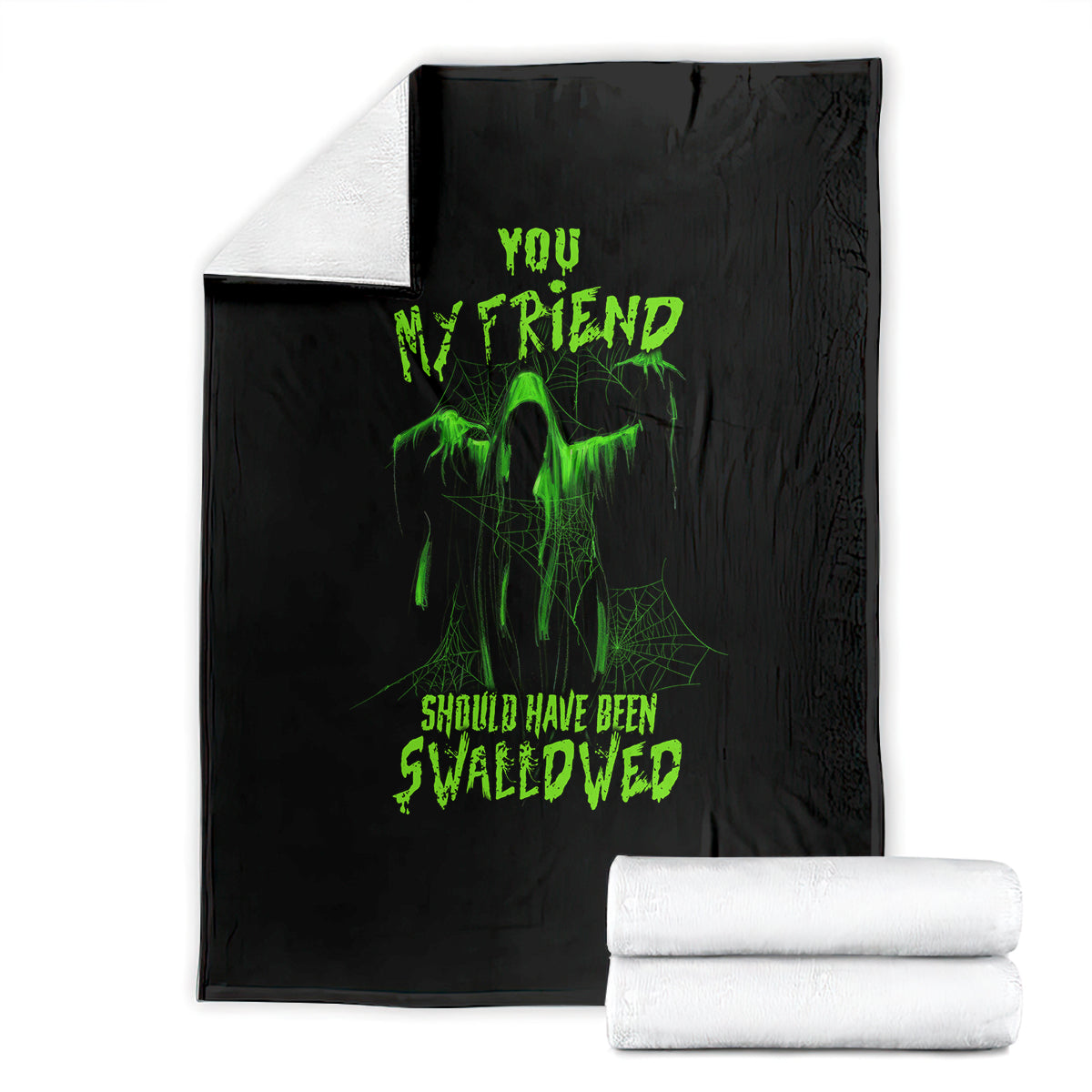 Black Halloween blanket folded with green skull graphic; stacked white towels