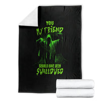 Black Halloween blanket folded with green skull graphic; stacked white towels
