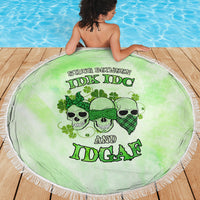 Round green beach blanket with skull faces graphic and fringed edge on deck