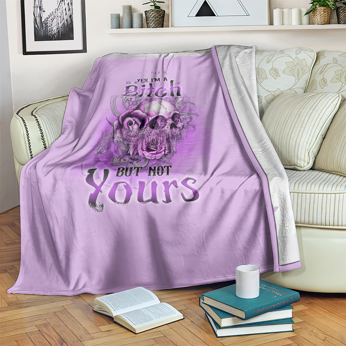 Purple blanket draped on a couch with floral skull art and “YES I'M A Bitch BUT NOT Yours”.