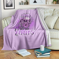 Purple blanket draped on a couch with floral skull art and “YES I'M A Bitch BUT NOT Yours”.