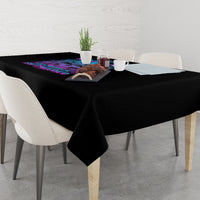 Black tablecloth with multicolor print on table surface, corner drape visible