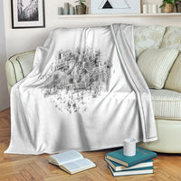 White throw blanket with black skeleton crest graphic and ribbon banner, draped on sofa