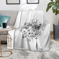 White graphic blanket with black skeleton skull emblem over gray sofa backrest