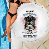 Round white beach blanket draped on poolside, multicolor warning magician graphic and tassel fringe