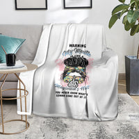White blanket with colorful illustrated head and warning quote, folded over couch