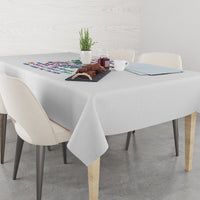 Grey tablecloth draped over dining table with colorful printed motif in center