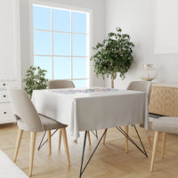 White tablecloth draped on dining table with colorful text-and-floral centerpiece