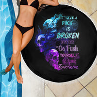 Round black beach blanket with skull flames artwork and multicolor lettering, white fringe