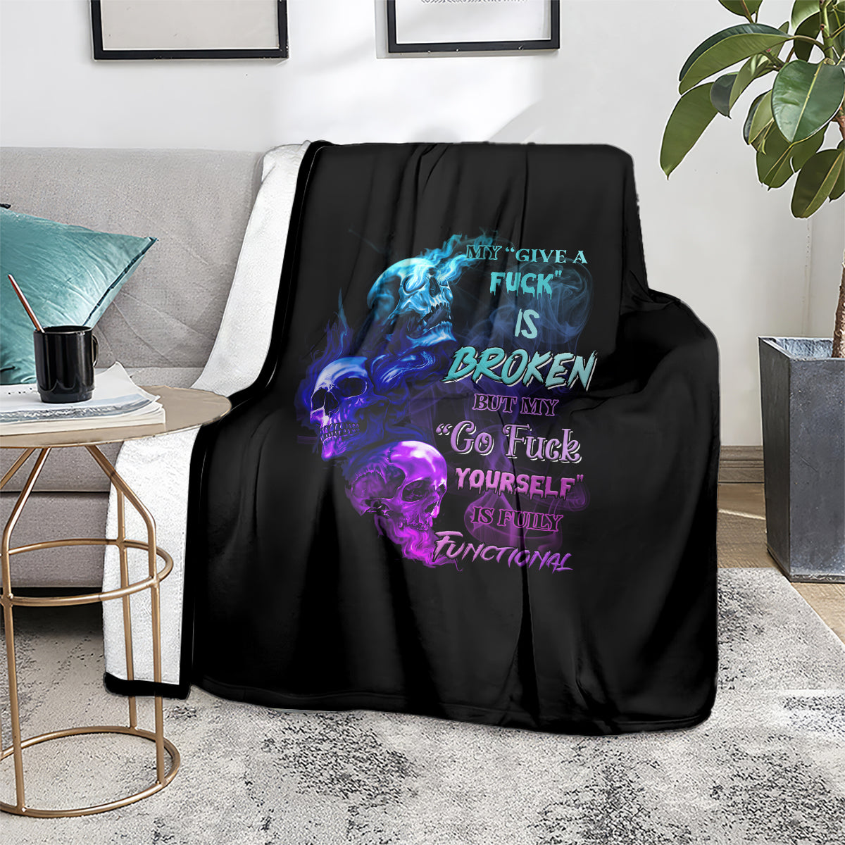 Black graphic throw blanket with blue and purple skull flame text, laid on couch