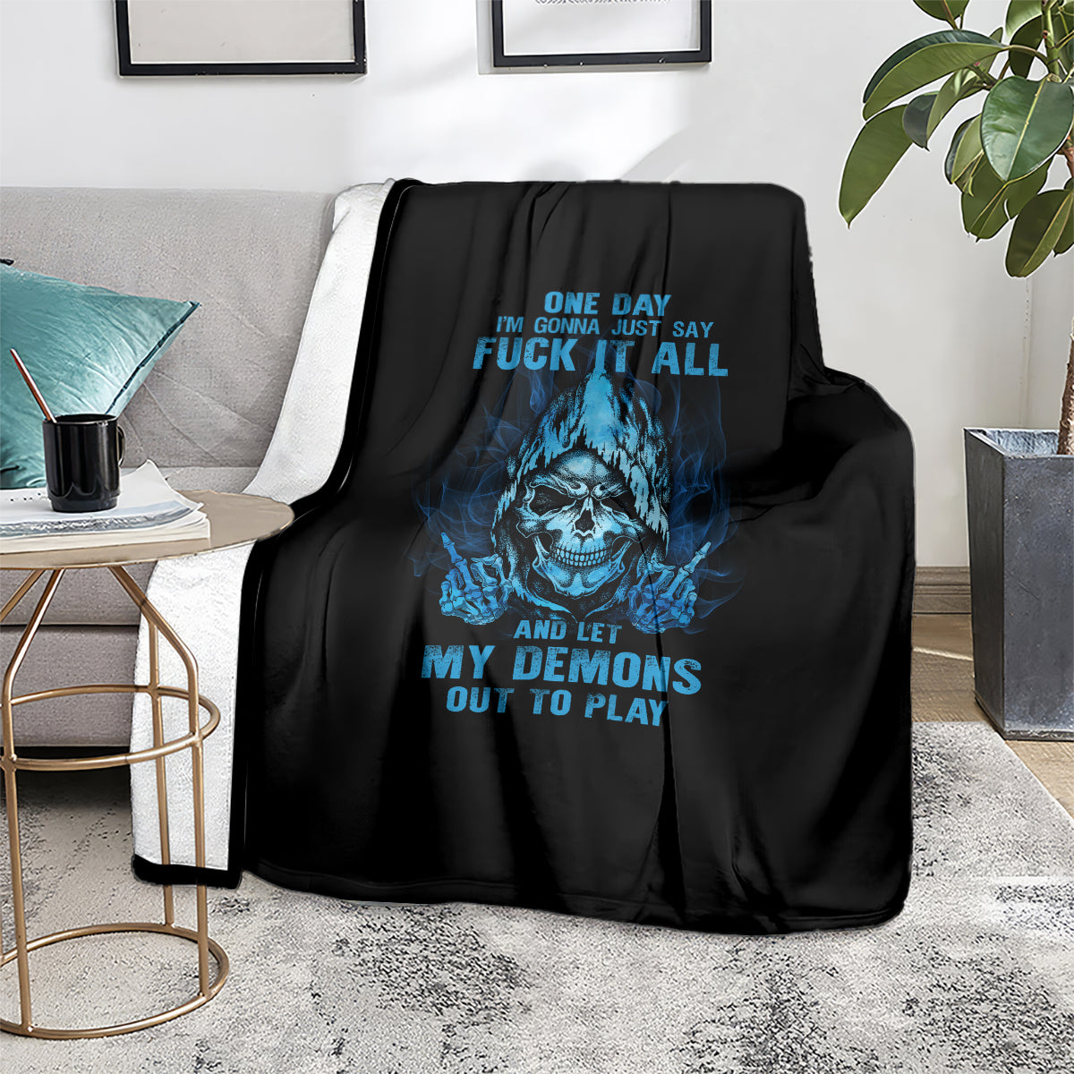 Black skull throw blanket with blue face graphic and bold text, draped on sofa