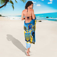Blue and yellow sarong with trident emblem and sunflower print, wrapped around body