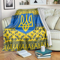 Blue and yellow patterned throw blanket with gold trident emblem, draped on sofa