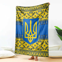 Blue and yellow throw blanket with large gold trident emblem, draped upright near pillows