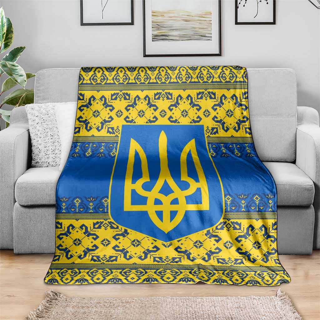 Blue and yellow ornate throw blanket with gold trident emblem, spread across gray couch