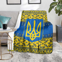 Blue and yellow patterned throw blanket with gold trident emblem, laid over couch